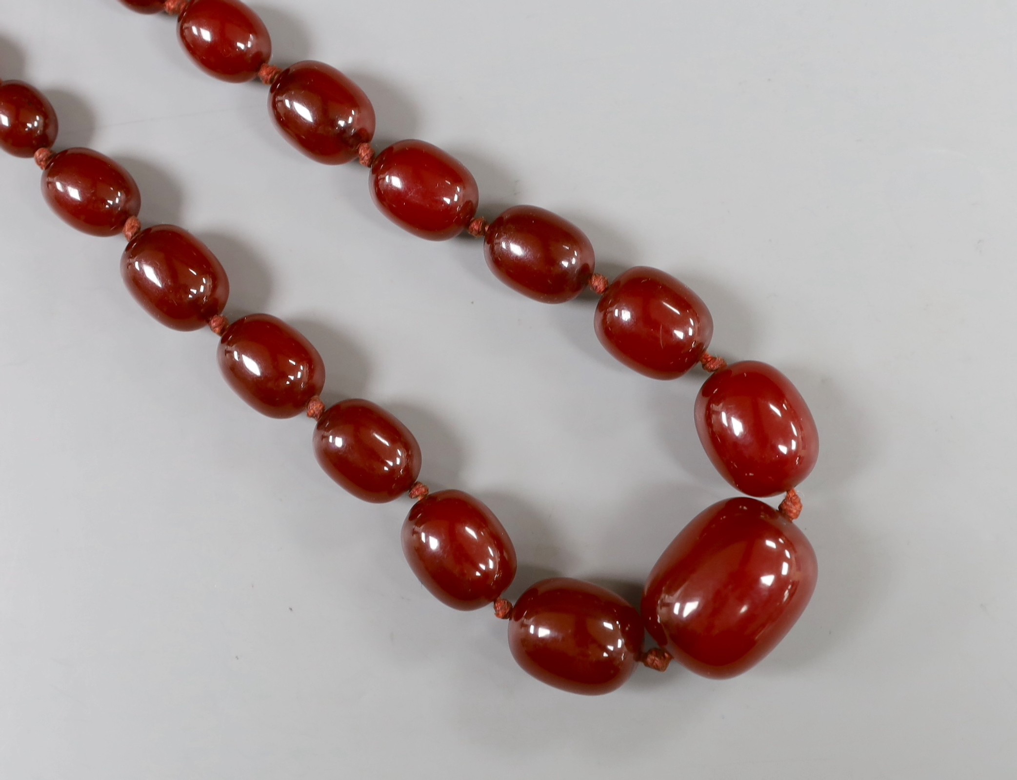 A single strand graduated oval simulated cherry amber bead necklace, 56cm, gross weight 75 grams.